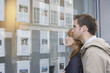 © moodboard - Side view of a young couple looking at window display at real estate office
