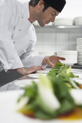 Canvas Print - Side view of a male chef preparing salad in kitchen