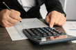 © Africa Studio - Close up view of man sitting at table with calculator, document and pen. Taxation concept