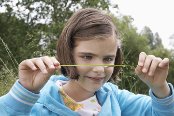 Wall Mural - Young girl examining caterpillar on grass outdoors