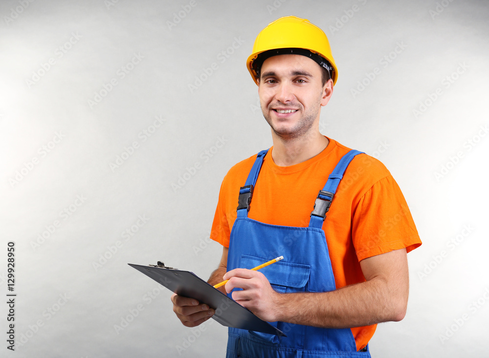 Handsome warehouse worker with clipboard  on light background