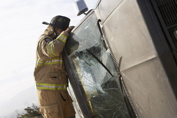 Wall Mural - Side view of a firefighter inspecting a crashed car