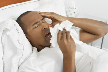 African American man suffering from cold in bed