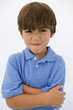 © MDBPIXS - Portrait of little boy making faces while standing with arms crossed isolated over white background