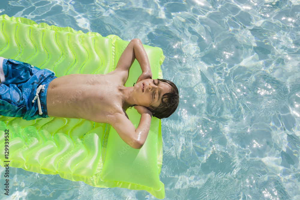 Boy floating on inflatable mattress in swimming pool Stock Photo ...