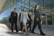 © MDBPIXS - Group of multiethnic businesspeople walking in front of office building
