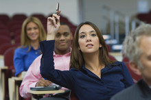 Female Executive Raising Hand During A Business Lecture Amid Colleagues