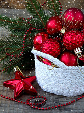 White Crochet Round Basket With Red Christmas Decorations On Wooden Background. New Year And Xmas Card Background. Copy Space. Selective Focus.