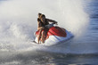 Young couple enjoying the ride of personal watercraft on lake