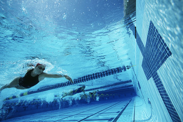 Professional female swimmers about to touch finishing line during a race