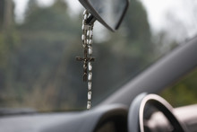 Rosary beads hanging on the rear view mirror of car