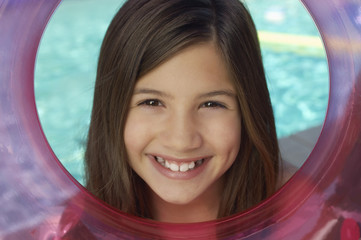 Wall Mural - Portrait of a happy cute preadolescent girl looking through inflatable ring