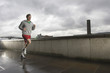 Young man jogging besides the Thames river in London on a stormy day