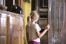 Rear View Of A Young Girl Opening Cupboard Door