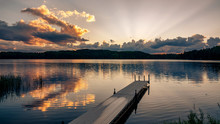 A Dock Jutts Out Into A Lake At Sunset On A Northern Wisconsin Lake.