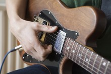 Closeup Of A Young Man Strumming Chord On Guitar
