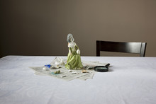 Closeup Of A Figurine With Magnifying Glass And Papers On Table
