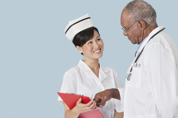 Poster - Two health professionals having a discussion over medical report against light blue background