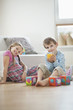 © MDBPIXS - Portrait of young boy drinking orange juice while sitting with sister on floor