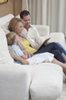 © MDBPIXS - Caucasian family of three using digital tablet while sitting on sofa