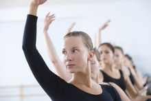 Beautiful Young Woman With Classmates Practicing At The Barre In Ballet Rehearsal Room