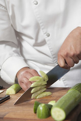 Canvas Print - Midsection of male chef slicing cucumber on chopping board