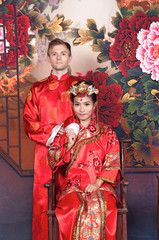 Wall Mural - Mixed Race Bride and Groom in Studio wearing traditional Chinese wedding outfits