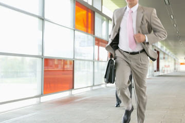 Midsection of businessmen rushing on railroad platform