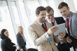 © MDBPIXS - Businessmen using digital tablet at convention center