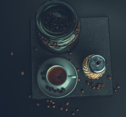 Wall Mural - Cappuccino. Concept. Glass jar with coffee beans and brown sugar cane on a dark background. Retro. Vintage. Top view.