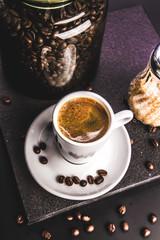 Wall Mural - Coffee. Concept. Glass jar with beans and brown sugar cane on a dark background. Retro. Vintage. Top view.