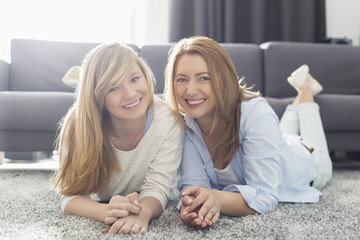 portrait of smiling mother and daughter lying on carpet