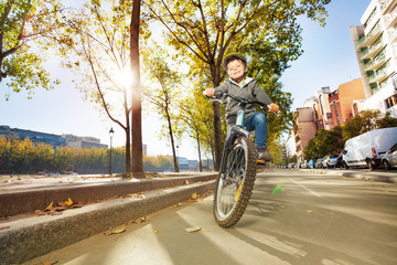 Wall Mural - Happy boy riding his bike at city park