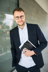 Wall Mural - Young hipster businessman in glasses near office outdoor