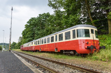 A Red And Cream Train Stationed Beside The Track