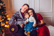 © nataliakabliuk - Portrait of affectionate family in christmas time. Family (mother, father, and little cute daughter) sitting near a Christmas tree and smiling face in the frame