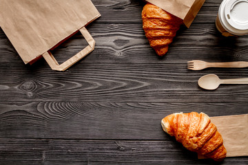 Wall Mural - cup coffee and bread in paper bag on wooden background