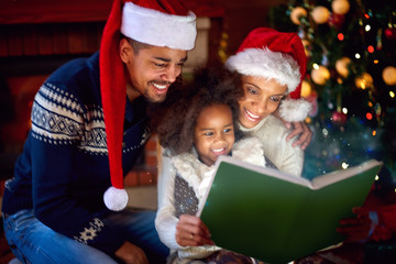 Wall Mural - Nice black kid with parents look at new book