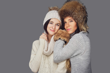 Wall Mural - Two women in winter clothes on white background.