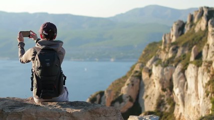 Wall Mural - Young woman uses a smartphone to video a beautiful view in the mountains
