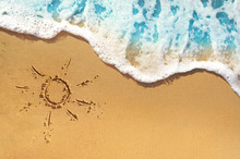 Soft Waves With Foam Blue Ocean Sea On A Golden Sunny Sandy Beach In Resort On Summer Vacation Rest. The Symbol Of The Sun Drawing On The Sand. Background Close Up.