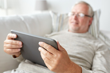 Sticker - senior man with tablet pc lying on sofa at home