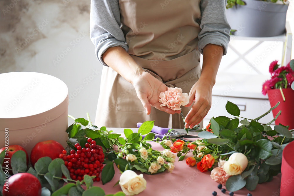 Female florist hands making composition with flowers closeup