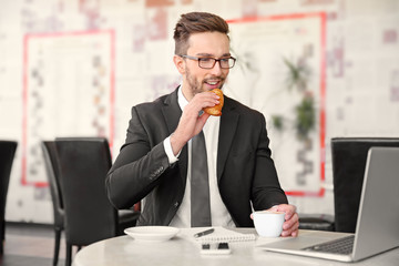 Sticker - Young businessman working in cafe while having snack