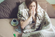© Artem - young woman sick with a cold lying in bed