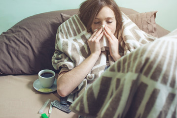 young woman sick with a cold lying in bed