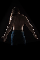 Brutal man bodybuilder athlete with long hair on a black background.