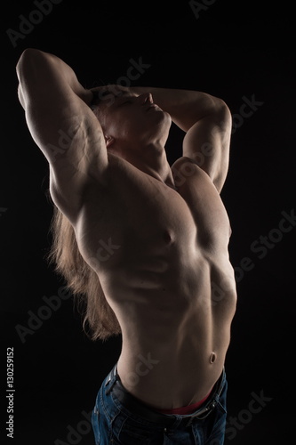 Brutal man bodybuilder athlete with long hair on a black background Plakát