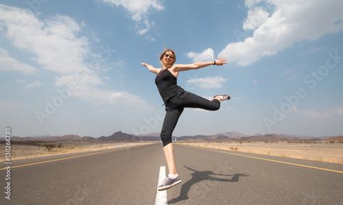 Young happy woman on an empty road in Oman desert. Tableau sur Toile