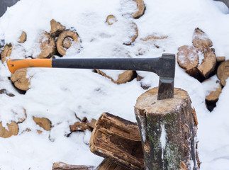 Axe in stump stored firewood in winter